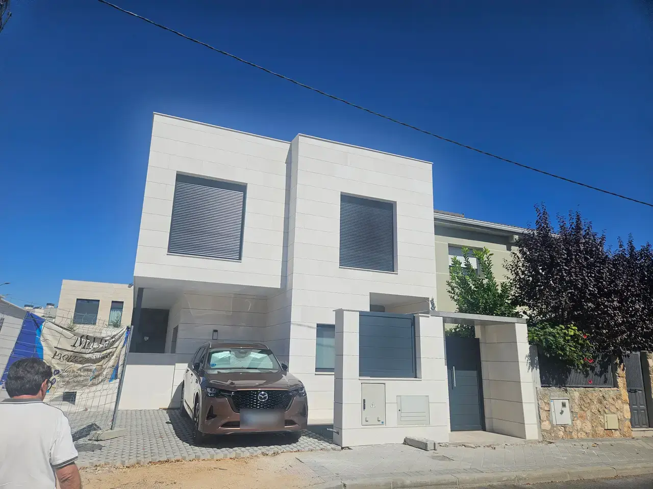 Vivienda unifamiliar terminada, con la fachada en tonos claros y el cerramiento de parcela